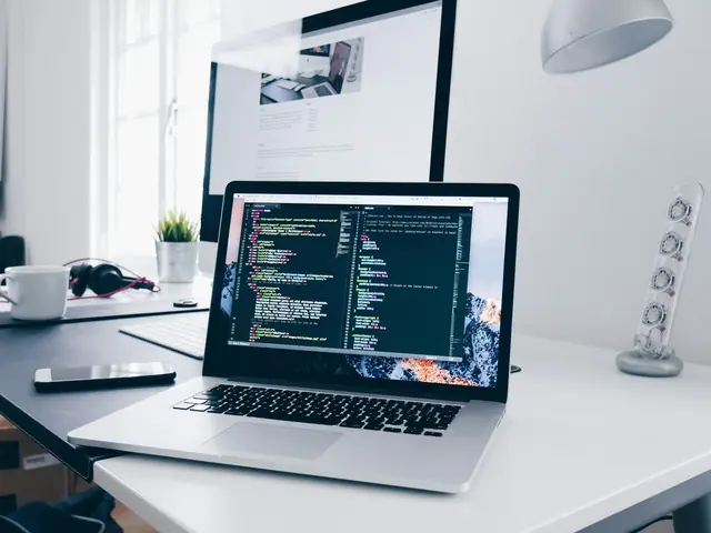 Mesa de trabajo con un portátil mostrando código y un monitor
